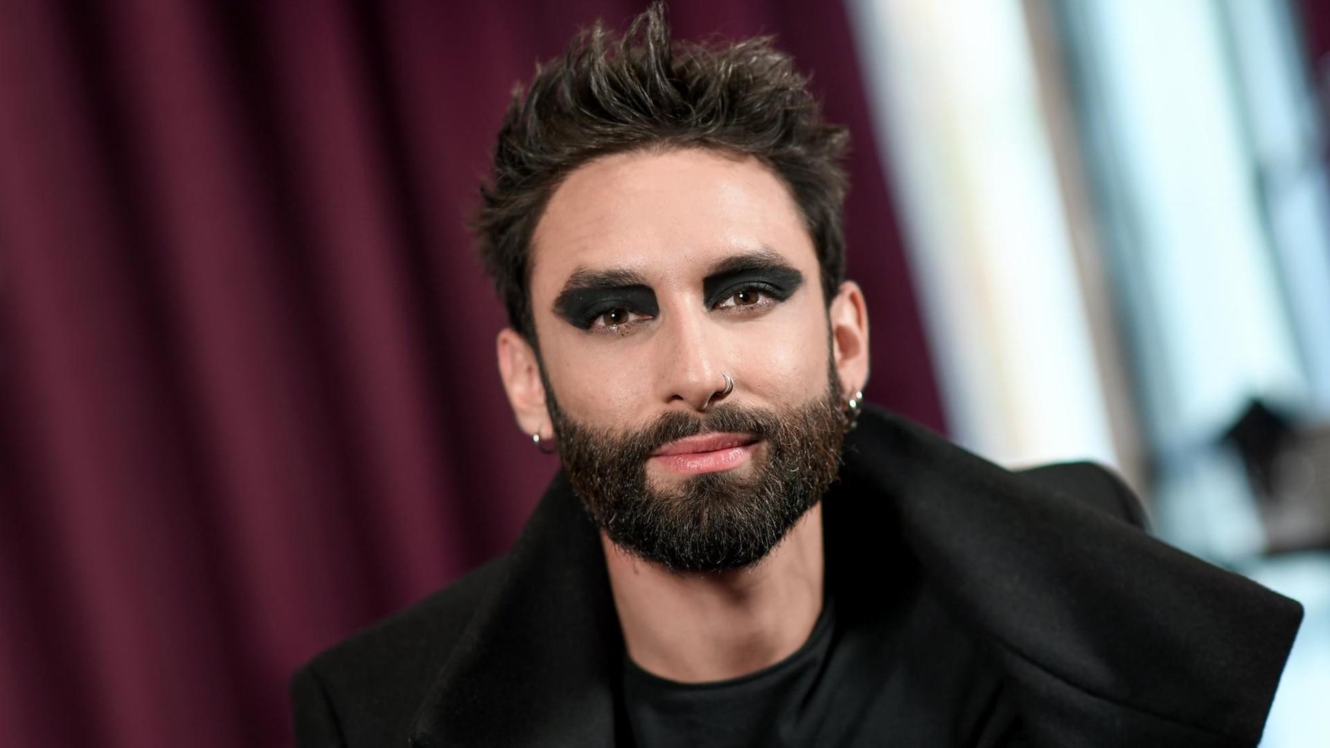 Nahnaufnahme des Künstlers Conchita Wurst, mit einem kurzen Haarschnitt und dunkel geschminkten Augen, vor einem weinroten Fenstervorhang. Nahnaufnahme des Künstlers Conchita Wurst, mit einem kurzen Haarschnitt und dunkel geschminkten Augen, vor einem weinroten Fenstervorhang.