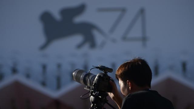 Eine Journalistin steht vor dem Logo der 74. Filmfestspiele in Venedig 2017