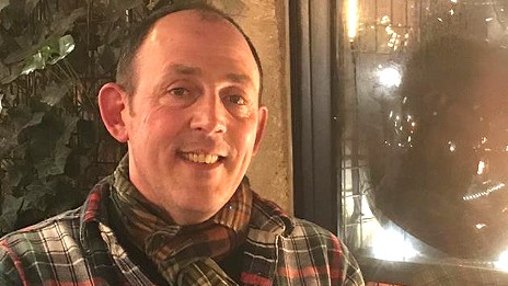 Ein Mann mit einem karierten Hemde steht vor einem Restaurant. Ein Mann mit einem karierten Hemde steht vor einem Restaurant.