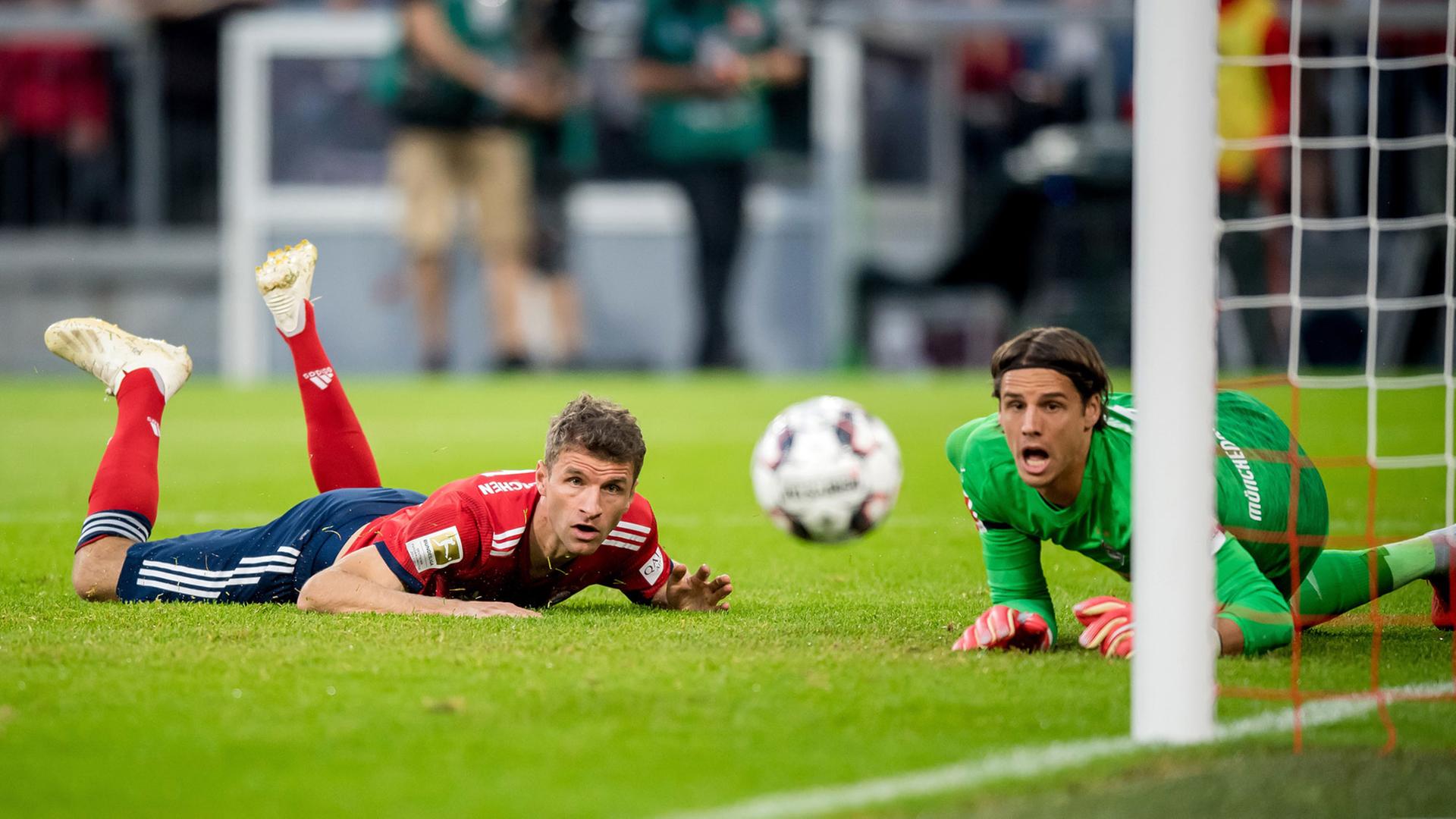 Beim Bundesligaspiel Bayern München - Borussia Mönchengladbach schauen Bayern-Spieler Thomas Müller und Gladbachs Torwart Yann Sommer auf dem Boden liegend einem Ball hinterher, der am Gladbacher Tor knapp vorbei geht.