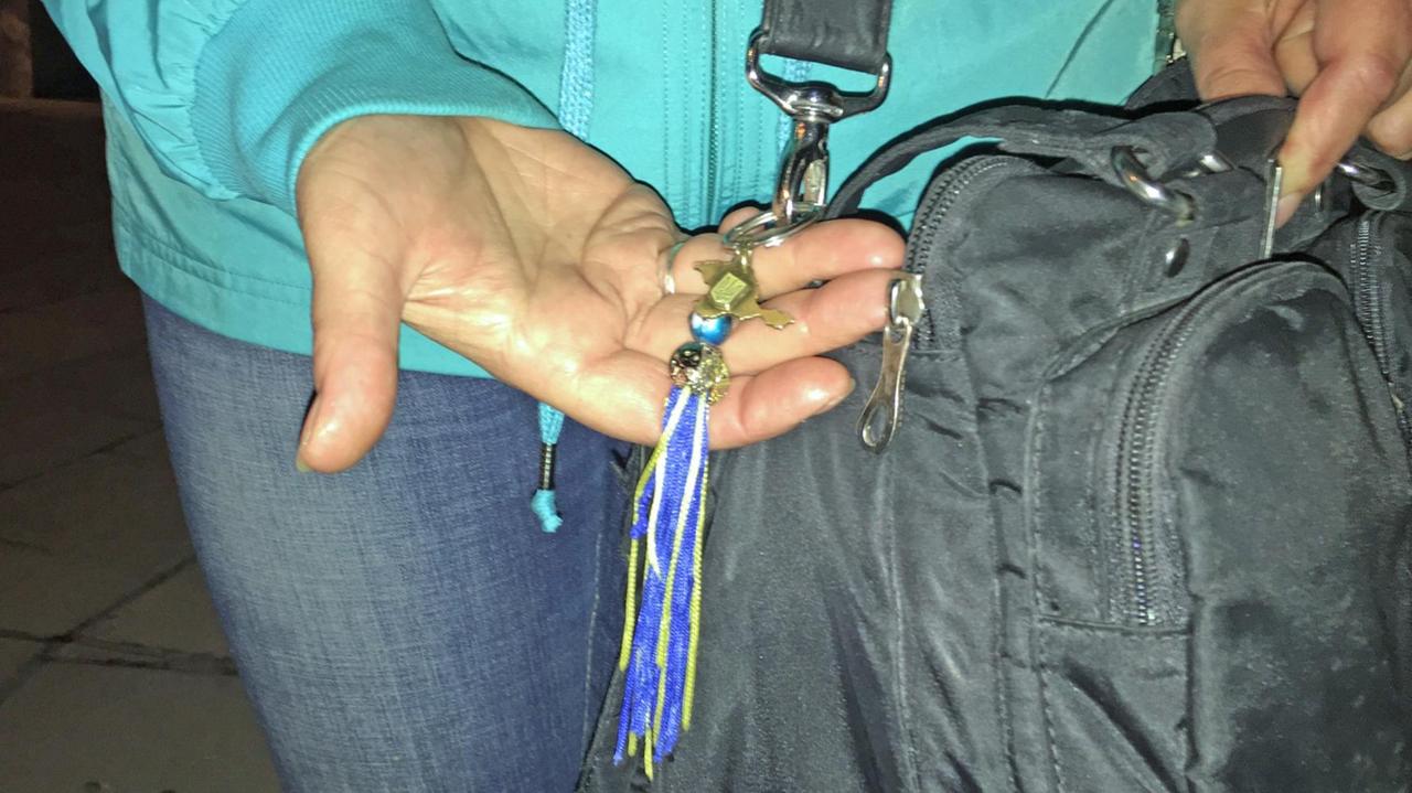 Auf der Hand von Tatjana liegt ein gelb-blauer Bommel und wird in die Kamera gehalten. Auf der Hand von Tatjana liegt ein gelb-blauer Bommel und wird in die Kamera gehalten.