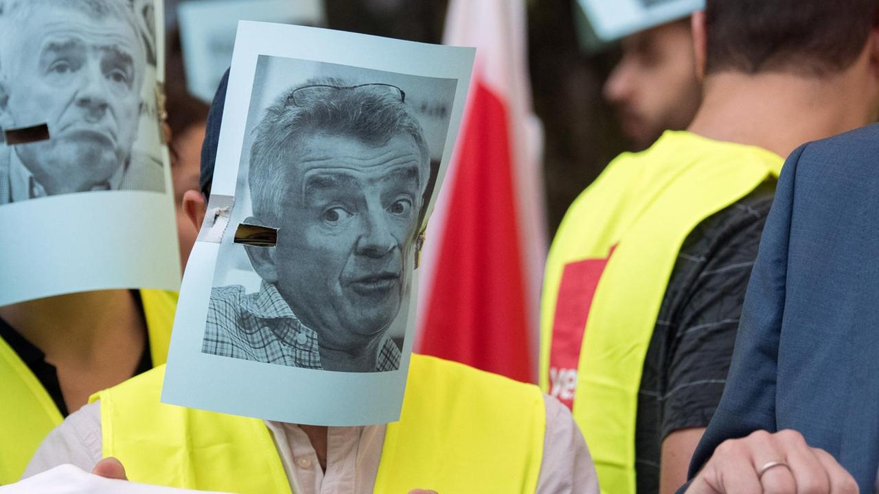 Mitarbeiter der Fluglinie Ryanair stehen während eines 24 Stunden dauernden Warnstreiks mit Masken des Vorstandsvorsitzender von Ryanair, Michael O'Leary, im Flughafen. Die Gewerkschaften Cockpit und Verdi hatten zu dem Warnstreik aufgerufen.
