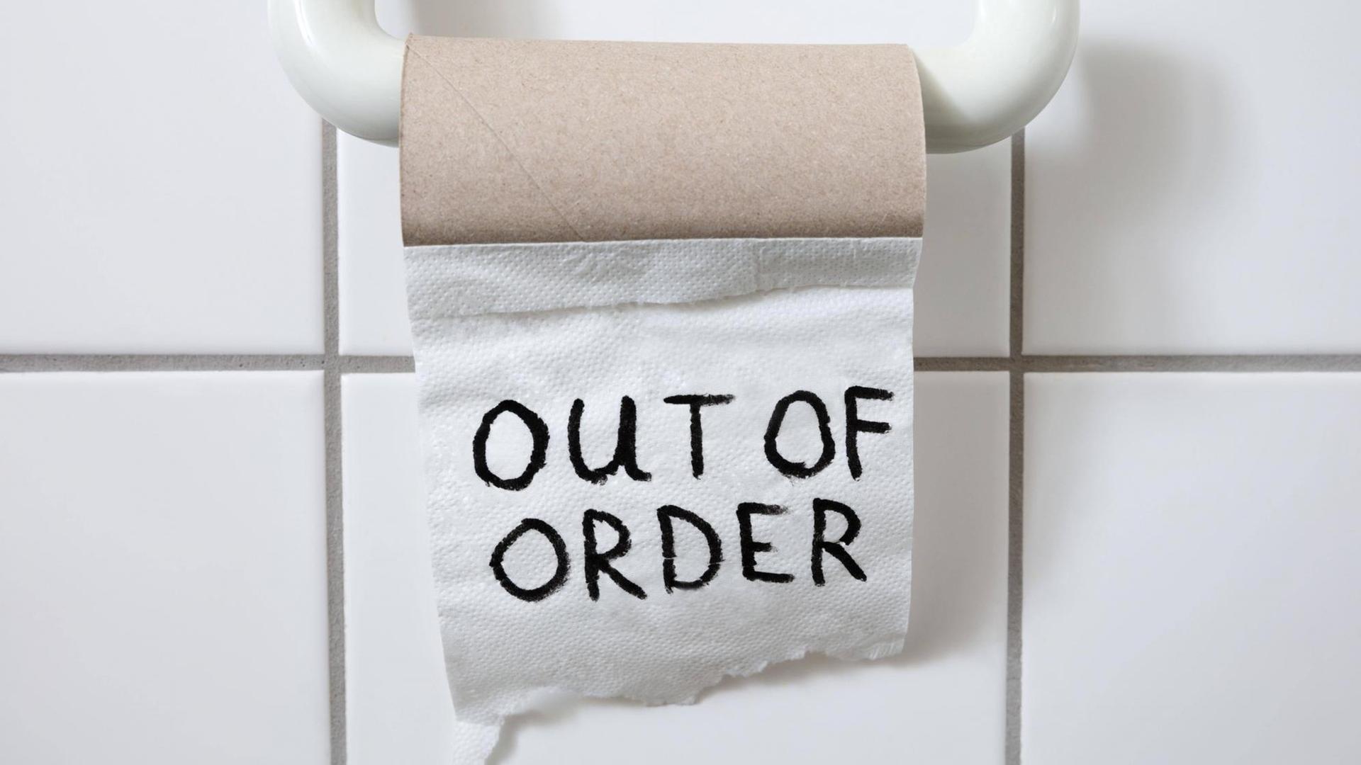 eine fast leere Toilettenpapierrolle auf derem letzten Blatt "out of order" steht eine fast leere Toilettenpapierrolle auf derem letzten Blatt "out of order" steht