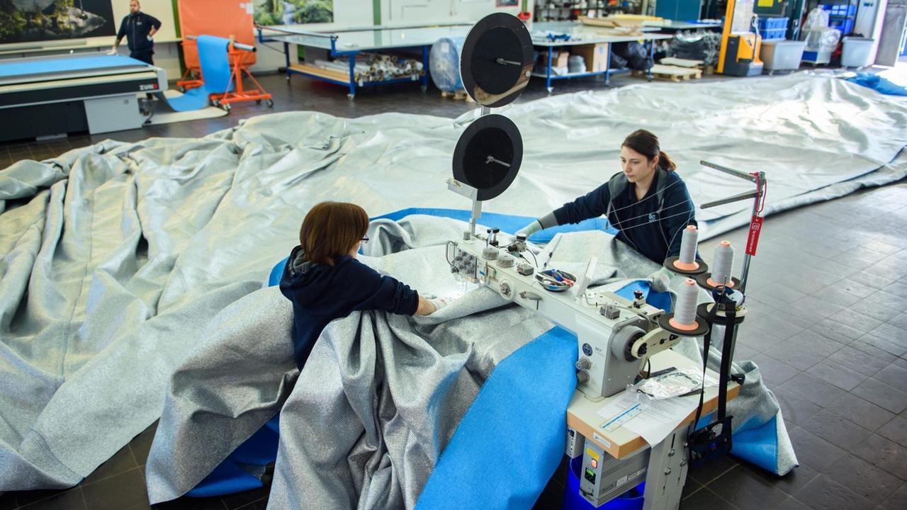 Zwei Frauen vernähen Stoffpanele für die Installation des Künstlers Christo am Arc de Triomphe in Paris. Zwei Frauen vernähen Stoffpanele für die Installation des Künstlers Christo am Arc de Triomphe in Paris.