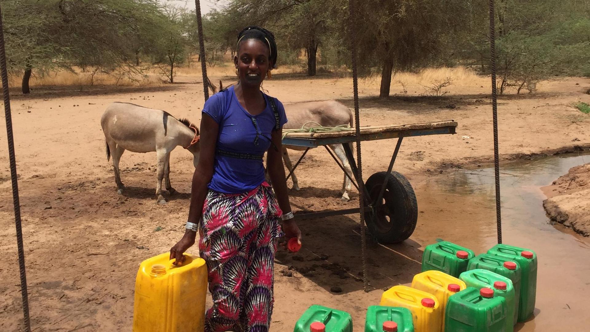 Ein junge Frau trägt einen Wasserkanister. Ein junge Frau trägt einen Wasserkanister.