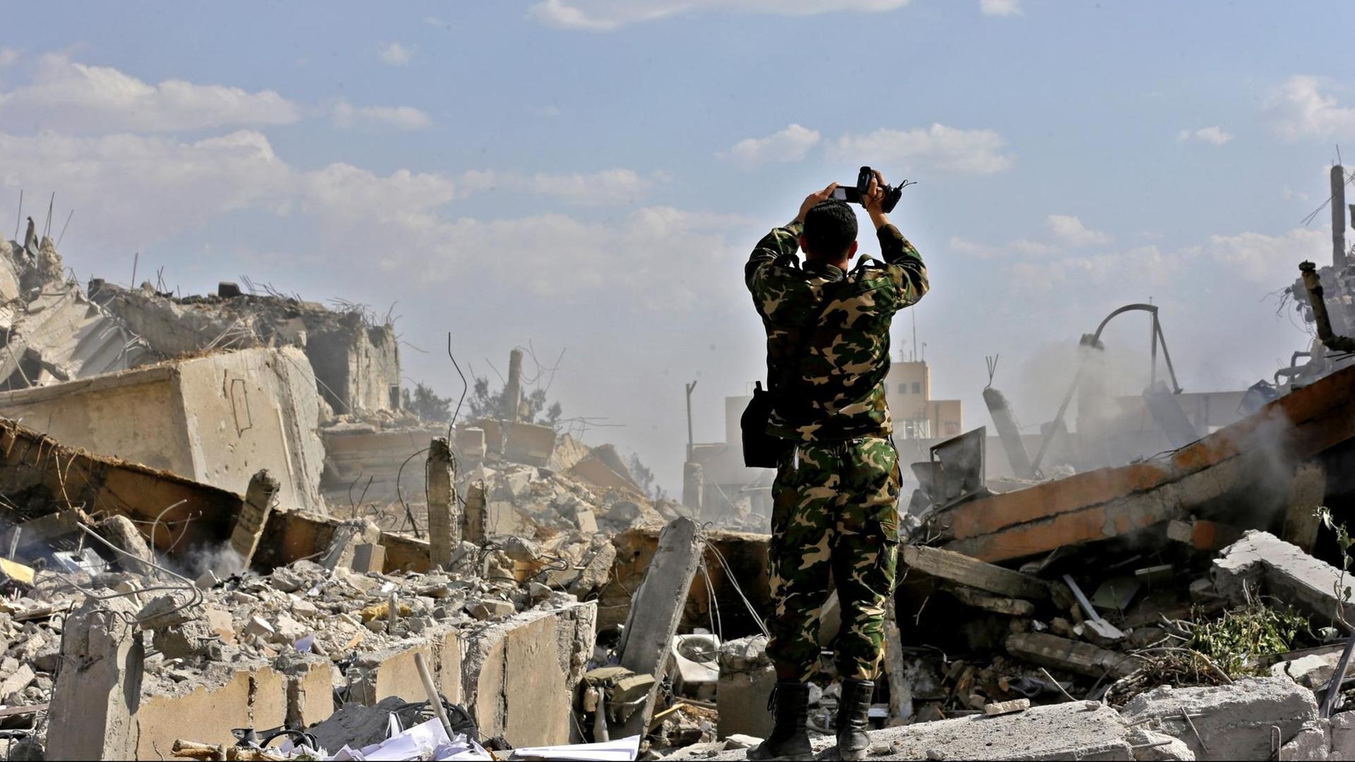 Ein syrischer Soldat filmt ein zerstörtes Gebäude des Forschungszentrums in Barzeh nördlich von Damaskus, das nach Angaben Syriens von den Luftschlägen der USA, Frankreichs und Großbritanniens getroffen worden sein soll Ein syrischer Soldat filmt ein zerstörtes Gebäude des Forschungszentrums in Barzeh nördlich von Damaskus, das nach Angaben Syriens von den Luftschlägen der USA, Frankreichs und Großbritanniens getroffen worden sein soll