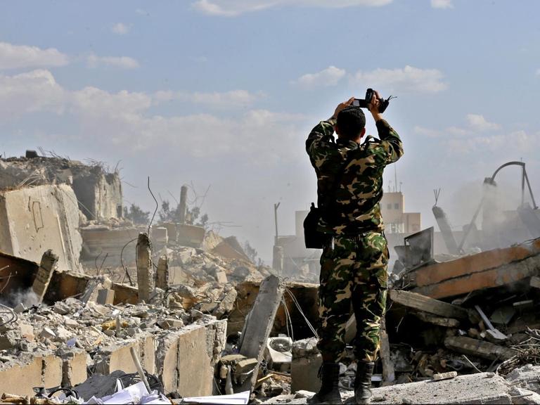 Ein syrischer Soldat filmt ein zerstörtes Gebäude des Forschungszentrums in Barzeh nördlich von Damaskus, das nach Angaben Syriens von den Luftschlägen der USA, Frankreichs und Großbritanniens getroffen worden sein soll