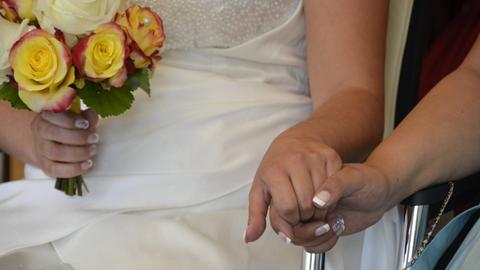 Zwei weibliche Hände berühren sich, sitzend, weißes Hochzeitskleid