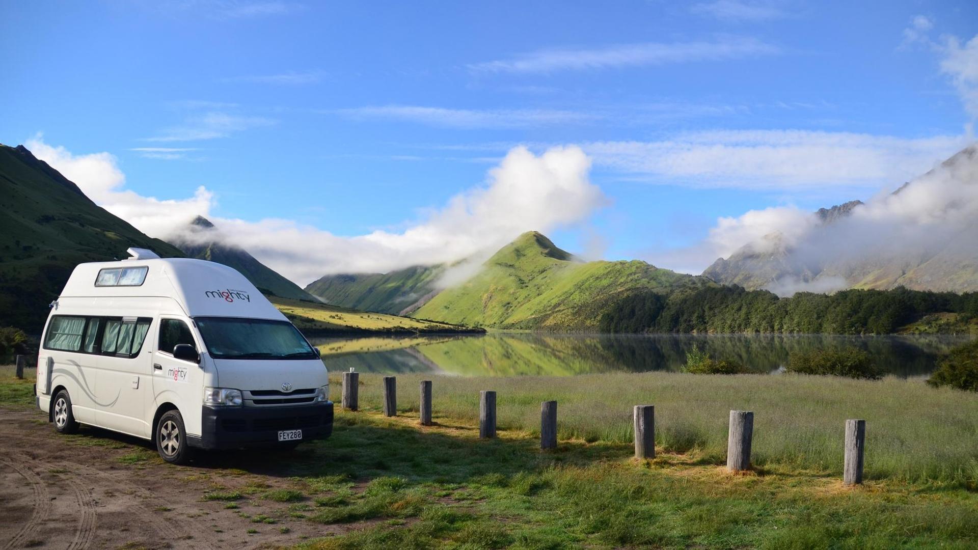 Ein Campingbus steht vor einem See und einer Berglandschaft in Neuseeland Ein Campingbus steht vor einem See und einer Berglandschaft in Neuseeland