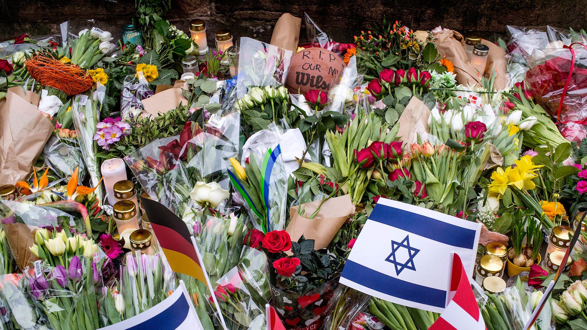 Vor der jüdischen Synagoge in Kopenhagen liegen nach dem Anschlag tausende Blumen; einige Menschen haben auch kleine Fahnen von Israel, Dänemark und Deutschland in das Blumenmeer gesteckt. Vor der jüdischen Synagoge in Kopenhagen liegen nach dem Anschlag tausende Blumen; einige Menschen haben auch kleine Fahnen von Israel, Dänemark und Deutschland in das Blumenmeer gesteckt.
