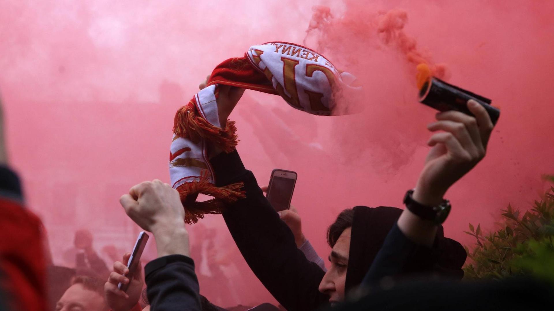 Ein FC Liverpool Fan mit Rauchbombe und Fanschal.