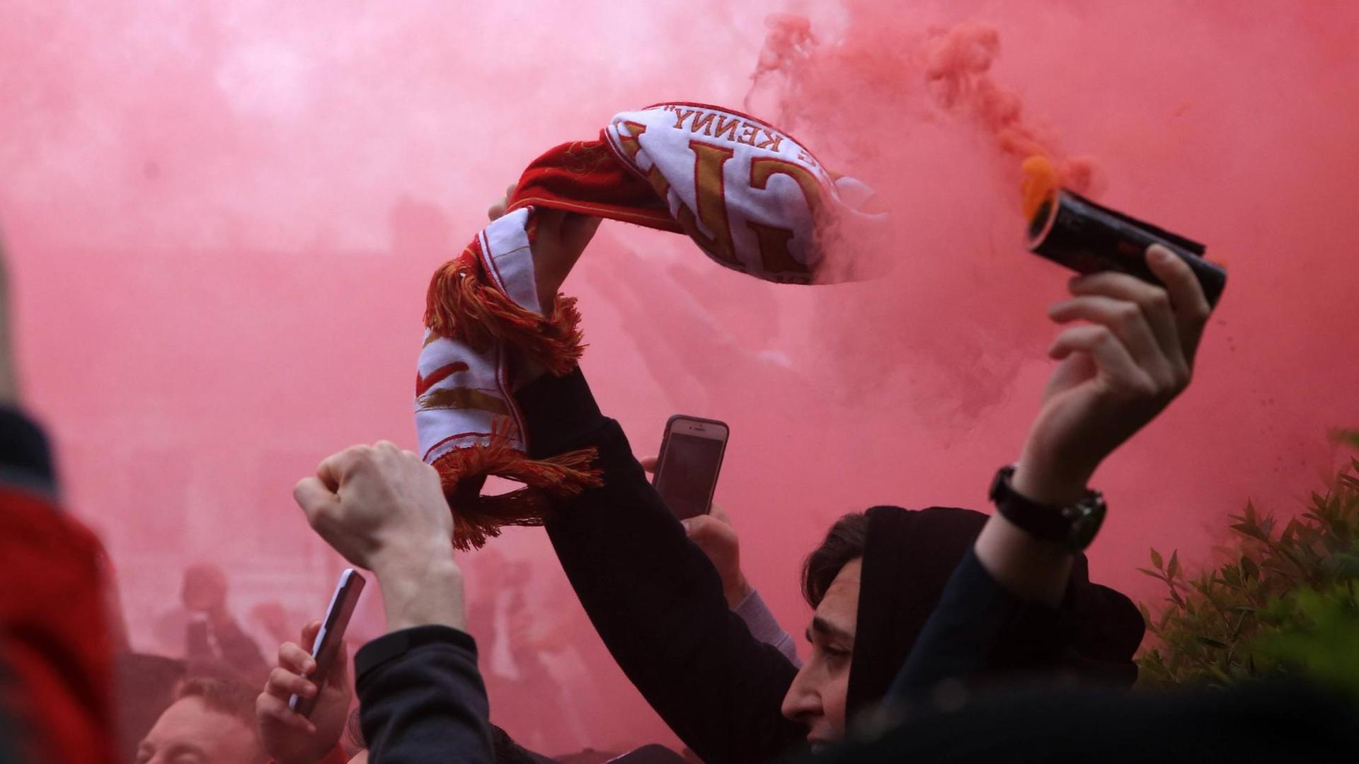 Ein FC Liverpool Fan mit Rauchbombe und Fanschal. Ein FC Liverpool Fan mit Rauchbombe und Fanschal.