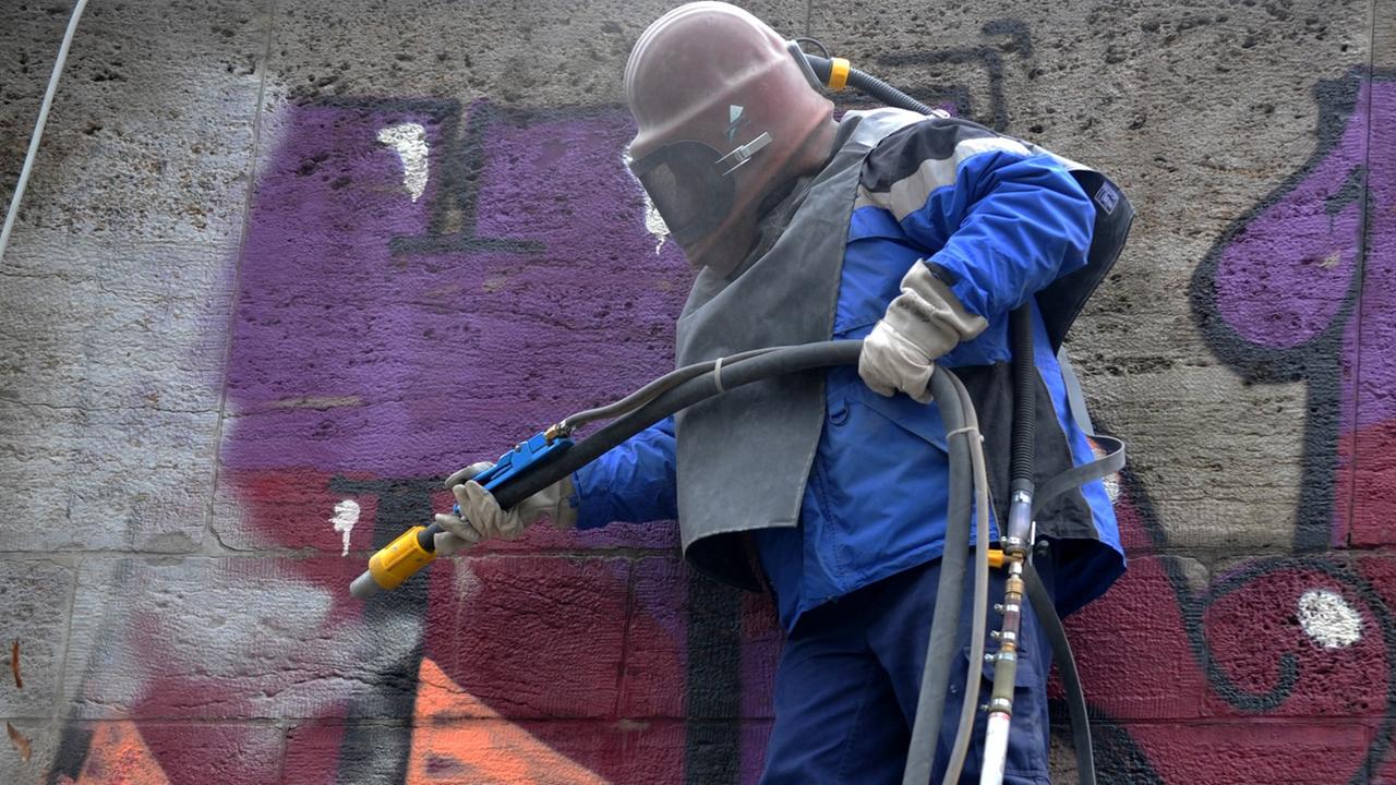 Ein Arbeiter des Baureferats mit Schutzhelm entfernt von der Ludwigsbrücke in München ein Graffiti. Ein Arbeiter des Baureferats mit Schutzhelm entfernt von der Ludwigsbrücke in München ein Graffiti.