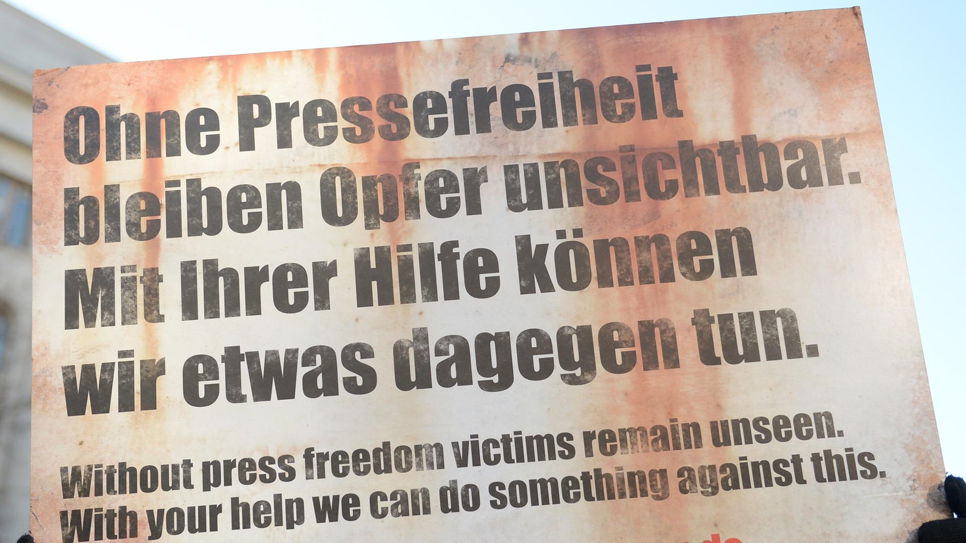 Ein Demonstrant der Organisation "Reporter ohne Grenzen" steht am 04.02.2014 vor der russischen Botschaft in Berlin. Er hält ein Schild hoch mit dem Text: "Ohne Pressefreiheit bleiben Opfer unsichtbar. Mit ihrer Hilfe können wir etwas dagegen tun.
