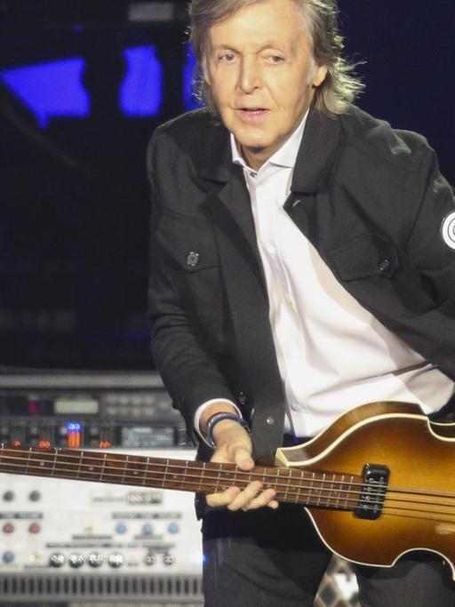 Paul McCartney mit einem Bass posierend auf der Bühne