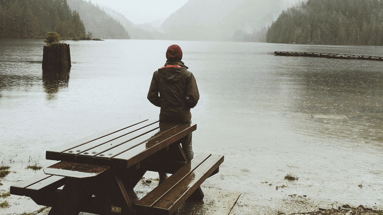 Eine Frau steht alleine vor einem See, mit dem Rücken zur Kamera. Eine Frau steht alleine vor einem See, mit dem Rücken zur Kamera.