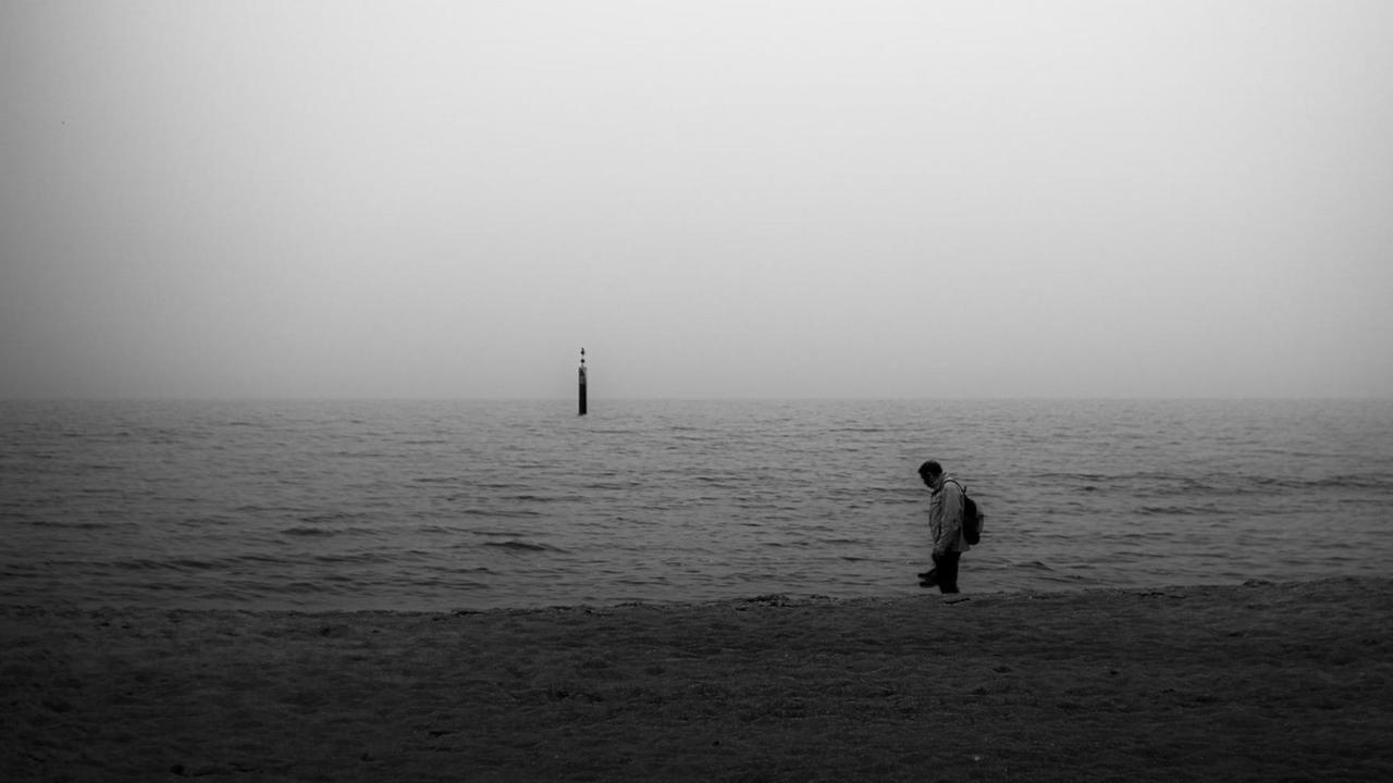 Ein Mann im Schattenriss steht am Meer, Ein Mann im Schattenriss steht am Meer,