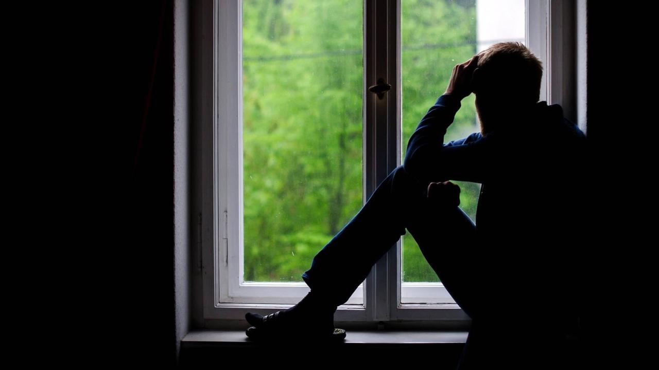 Ein Mann sitzt an einem Fenster und schaut raus Ein Mann sitzt an einem Fenster und schaut raus