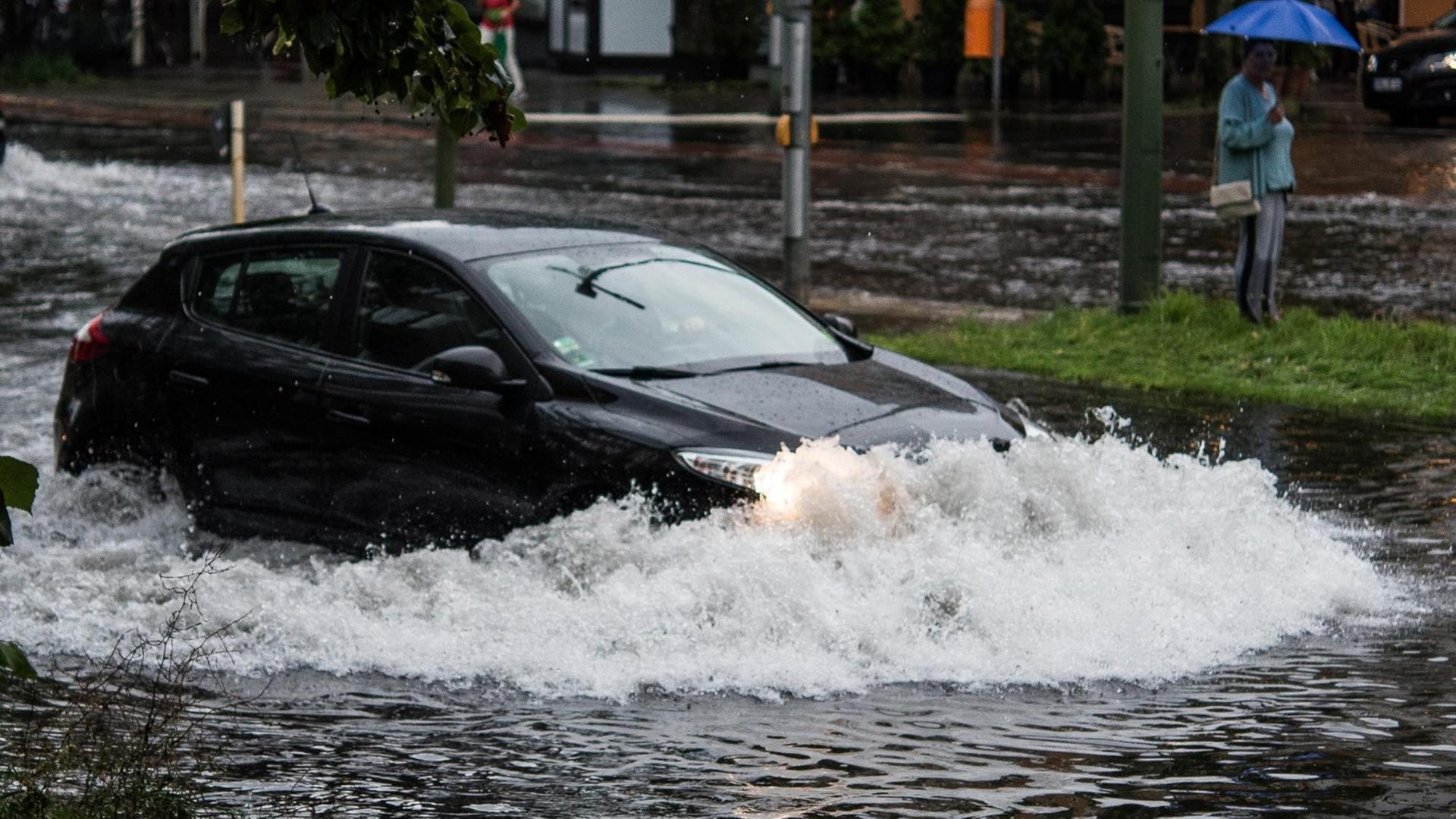 Ein Pkw fährt in Berlin nach einem Gewitter und starken Regenfällen durch die Wassermassen in der Breiten Straße. Ein Pkw fährt in Berlin nach einem Gewitter und starken Regenfällen durch die Wassermassen in der Breiten Straße.