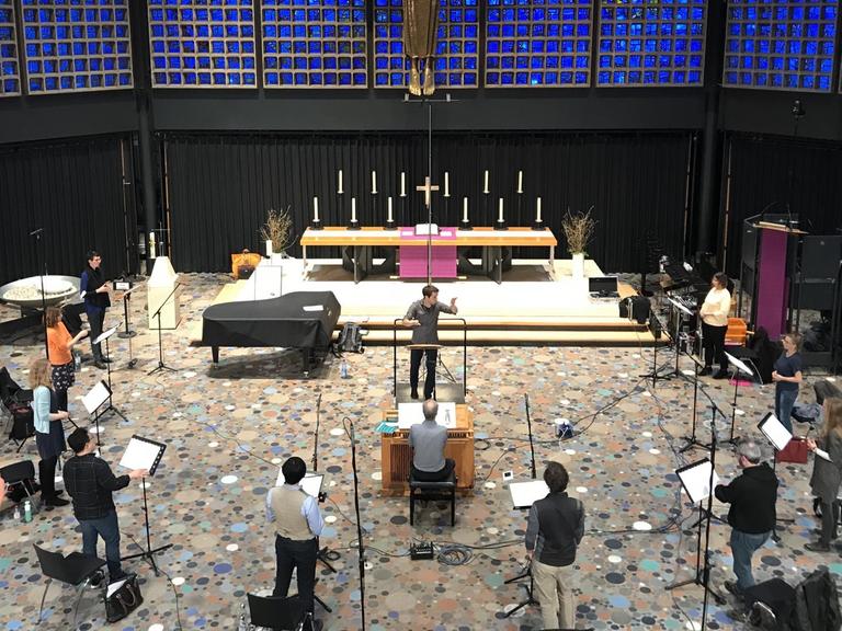 Blick von der Empore hinunter ins Kirchenschiff, wo die Sängerinnen und Sänger mit großem Abstand stehen und proben.