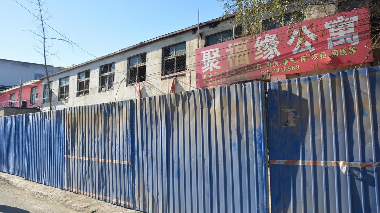 Ein ausgebranntes Appartementhaus in Peking wird von einem blauen Bauzaun gesichert. Ein ausgebranntes Appartementhaus in Peking wird von einem blauen Bauzaun gesichert.