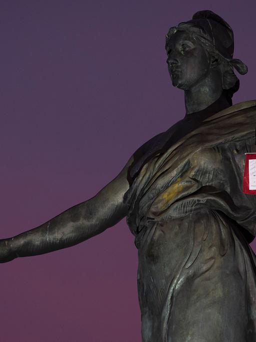 Französische Flagge vor einer Frauenstatue vor Nachthimmel