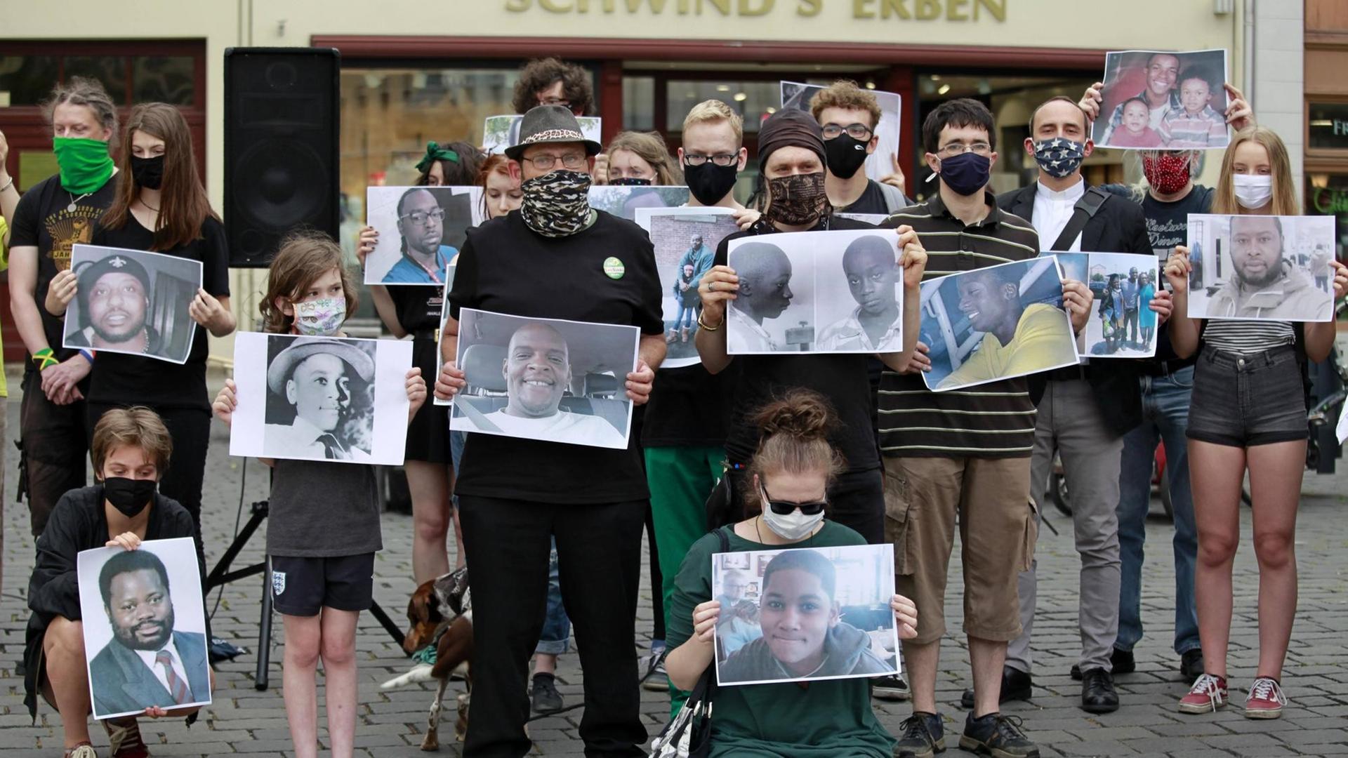 Bei einer "Black Lives Matter"-Mahnwach in Görlitz halten Demonstranten Bilder mit den Porträts von Opfern rassistischer Gewalt hoch.