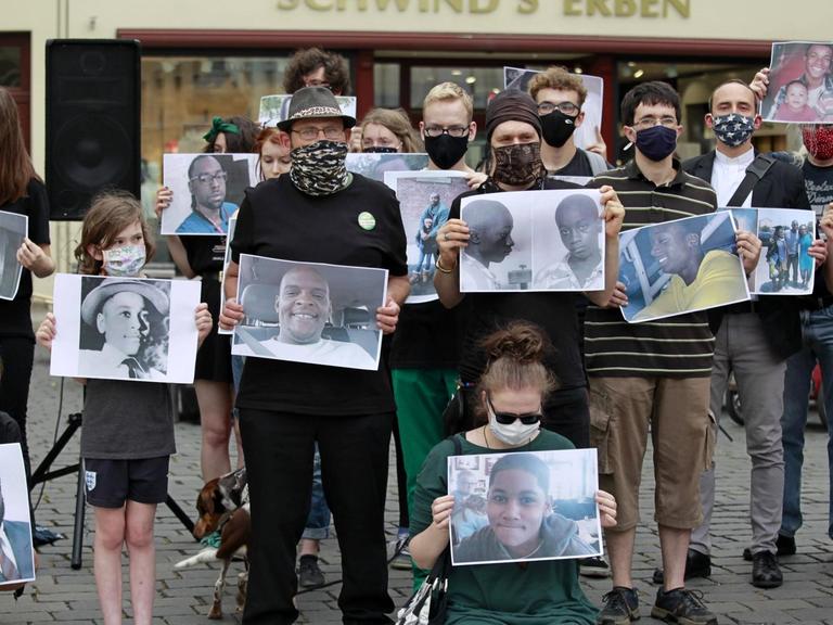 Bei einer "Black Lives Matter"-Mahnwach in Görlitz halten Demonstranten Bilder mit den Porträts von Opfern rassistischer Gewalt hoch.