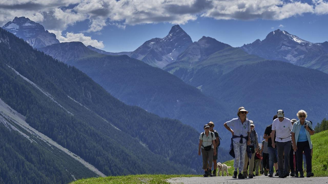 Mehrere Menschen laufen bei einem Spaziergang während des Davos Festivals 2020 vor Schweizer Bergkulisse. Mehrere Menschen laufen bei einem Spaziergang während des Davos Festivals 2020 vor Schweizer Bergkulisse.
