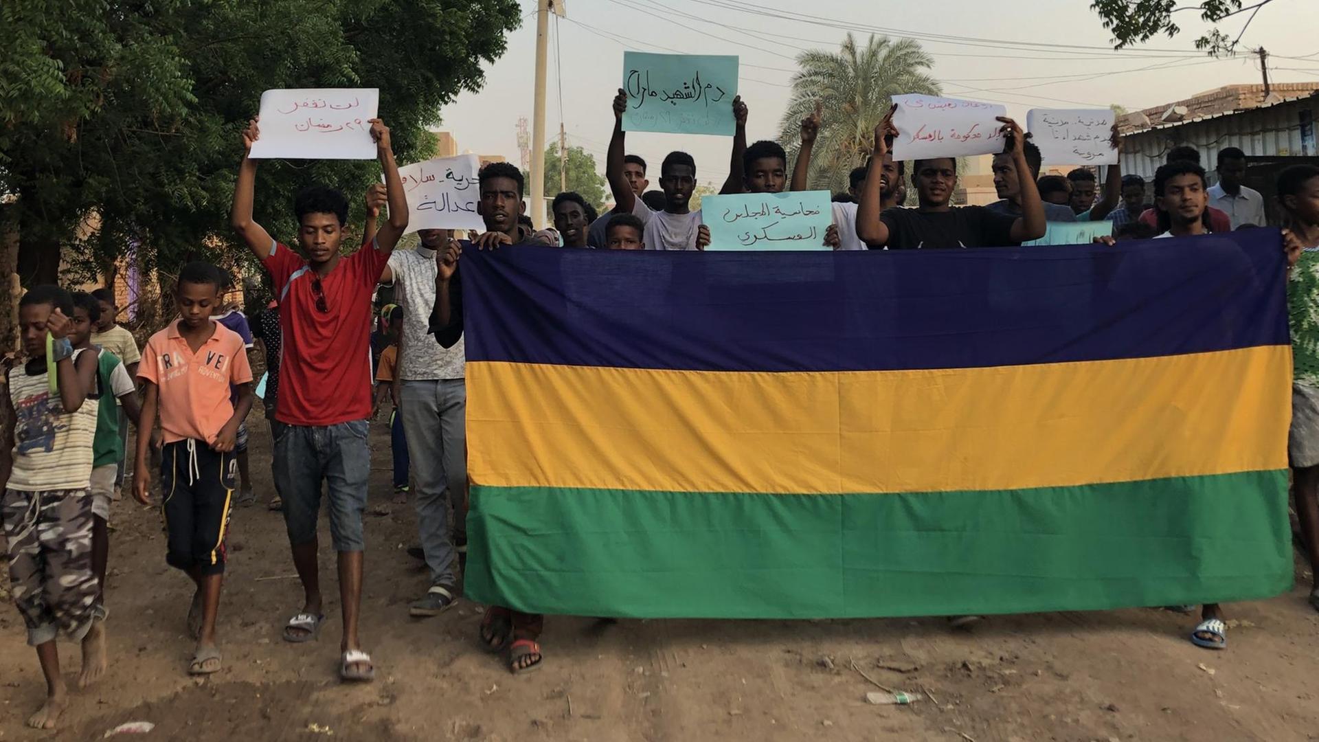 Demonstrierende im Sudan halten Schilder hoch Demonstrierende im Sudan halten Schilder hoch