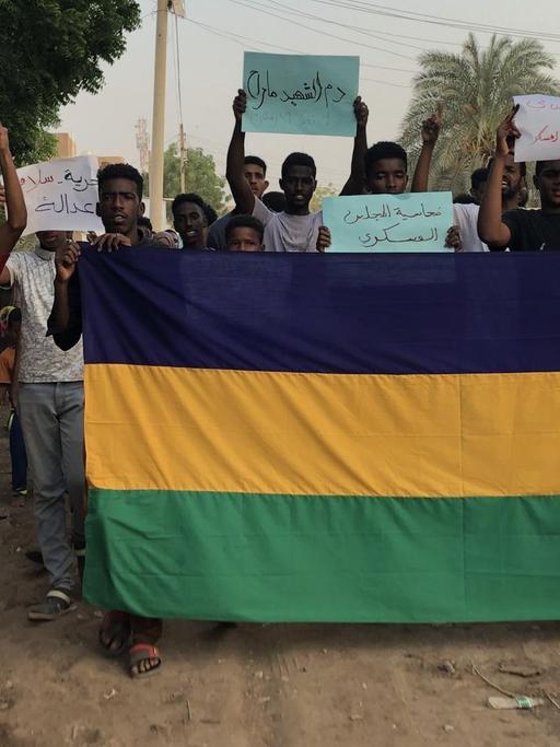 Demonstrierende im Sudan halten Schilder hoch