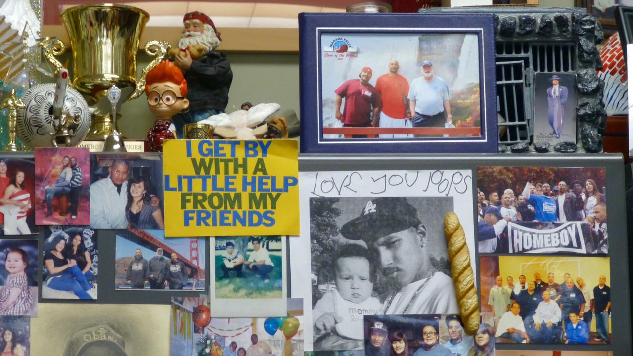 Ein Regal u.a. mit Fotos, Nippes, einem Pokal und der Textzeile aus einem Beatles-Song "I get by with a little help from my friends" Ein Regal u.a. mit Fotos, Nippes, einem Pokal und der Textzeile aus einem Beatles-Song "I get by with a little help from my friends"