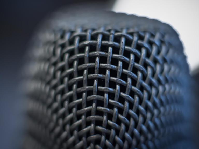 Das Bild zeigt eine Detail-Nahaufnahme eines Mikrofons - nur ein kleiner Teil der Mikrofonoberfläche ist fokussiert und scharf, der Rest des Mikrofons verschwindet in Unschärfe.