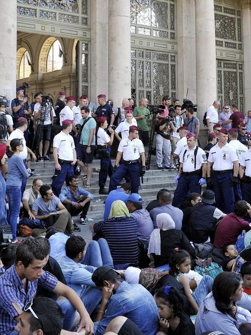 Zahlreiche Flüchtlinge sitzen vor dem Budapester Ostbahnhof, der von der Polizei abgeriegelt ist.