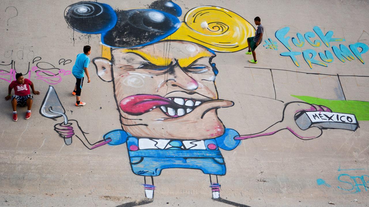 Kinder spielen am 23.06.2016 neben einer Graffiti-Karikatur, die Donald Trump im Flussbett des Rio Grande, zeigt. Kinder spielen am 23.06.2016 neben einer Graffiti-Karikatur, die Donald Trump im Flussbett des Rio Grande, zeigt.