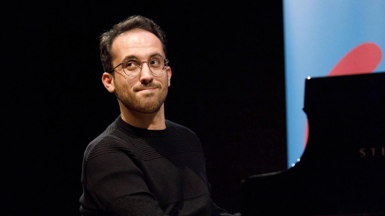 Igor Levit schaut am Flügel sitzend verschmitzt zur Seite. Igor Levit schaut am Flügel sitzend verschmitzt zur Seite.