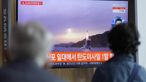 Passanten schauen auf einen Fernsehschirm in einem Bahnhof in Seoul. In einer Nachrichtensendung wird ein Bild der von Nordkorea abgefeuerten Rakete gezeigt.