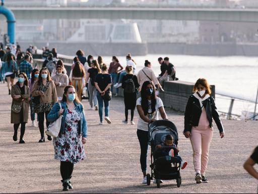Menschen mit Masken spazieren am Rheinufer in Köln, aufgenommen am 25.2.2021