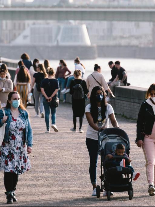 Menschen mit Masken spazieren am Rheinufer in Köln, aufgenommen am 25.2.2021