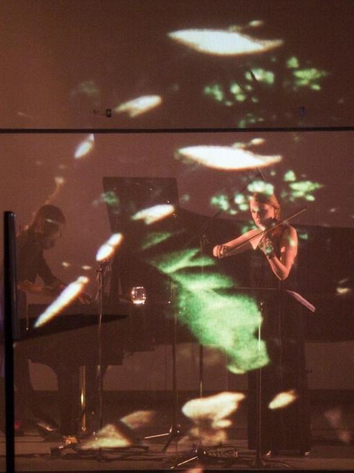 Das Duo Hellqvist/Amaral auf der Bühne mit Lichtreflexen auf einem Gaze-Vorhang