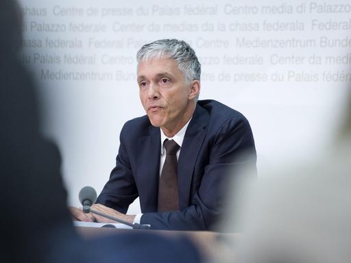 Foto vom oberste Strafermittler der Schweiz, Michael Lauber, bei einer Pressekonferenz durch zwei Journalisten hindurch