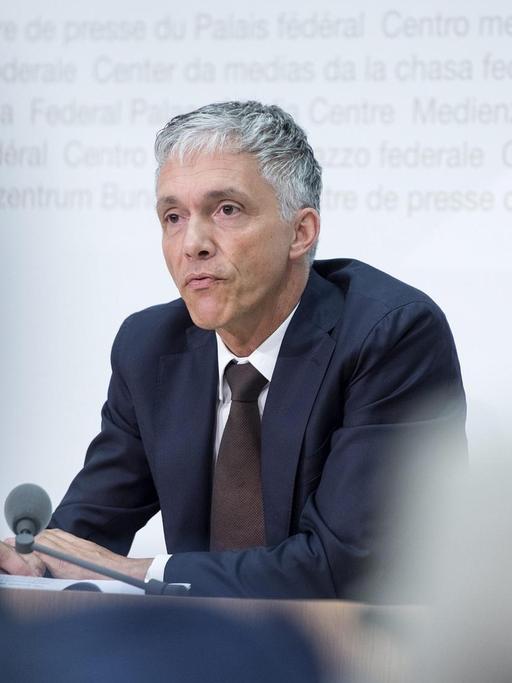 Foto vom oberste Strafermittler der Schweiz, Michael Lauber, bei einer Pressekonferenz durch zwei Journalisten hindurch