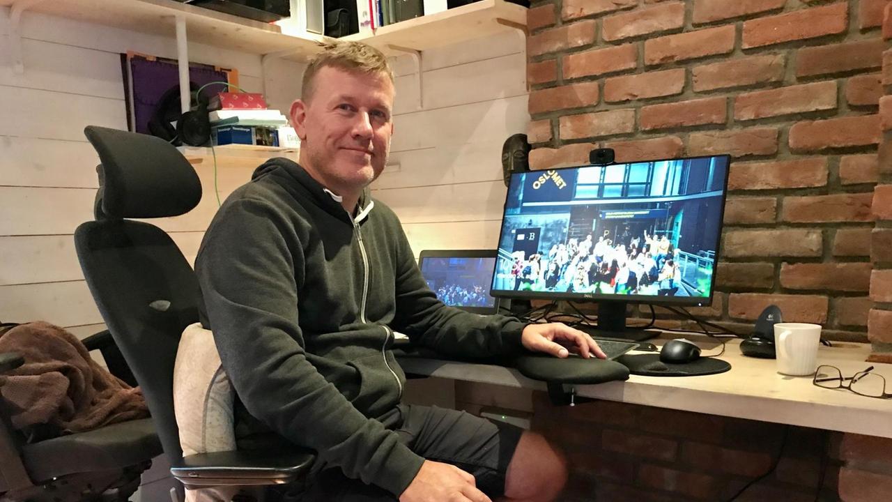 Ein Mann in kurzen Hosen und Sweater sitzt vor seinem PC am Schreibtisch. Ein Mann in kurzen Hosen und Sweater sitzt vor seinem PC am Schreibtisch.