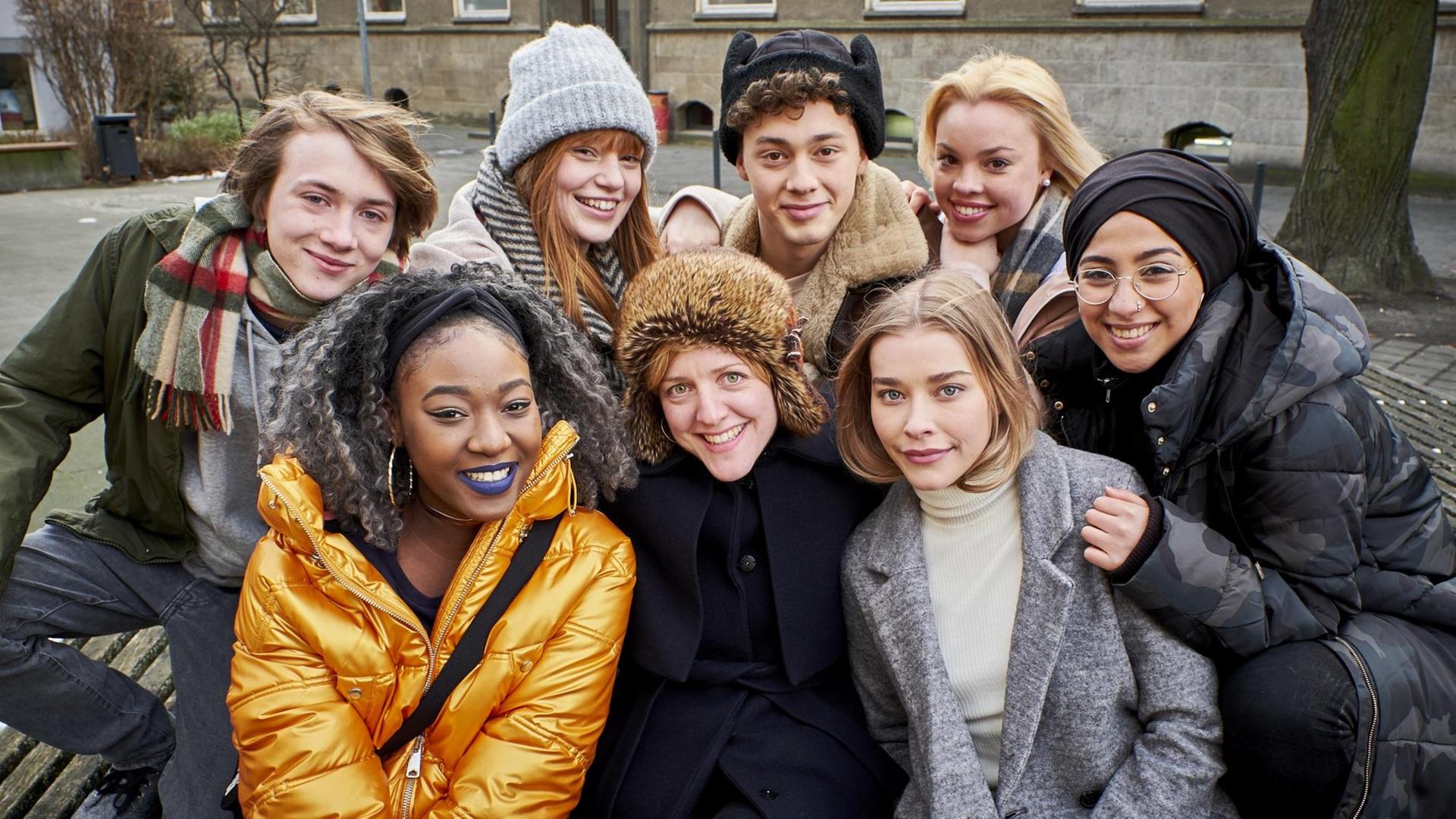 Das Gruppenfoto zeigt acht junge Darsteller - zwei junge Männer, sechs junge Frauen in Winterkleidung - aus der Serie "Druck", die die Alltagsgeschichten von Jugendlichen auf dem Weg zum Abitur erzählt.