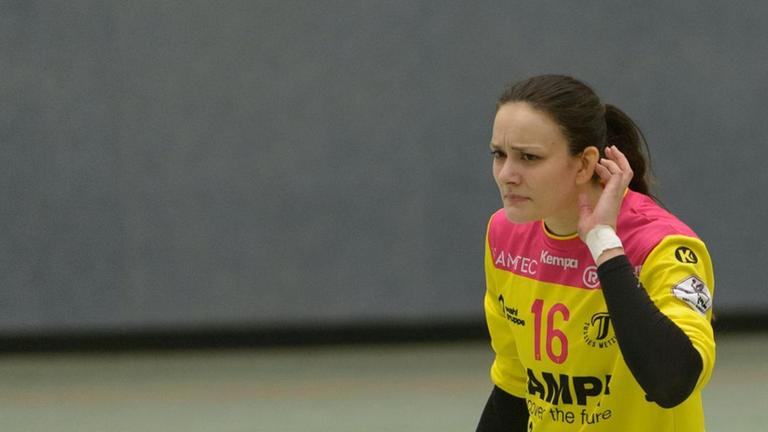Eine Handballspielerin führt die linke Hand zu ihrem linken Ohr, um etwas zu hören. Sie schaut fragend. Eine Handballspielerin führt die linke Hand zu ihrem linken Ohr, um etwas zu hören. Sie schaut fragend.