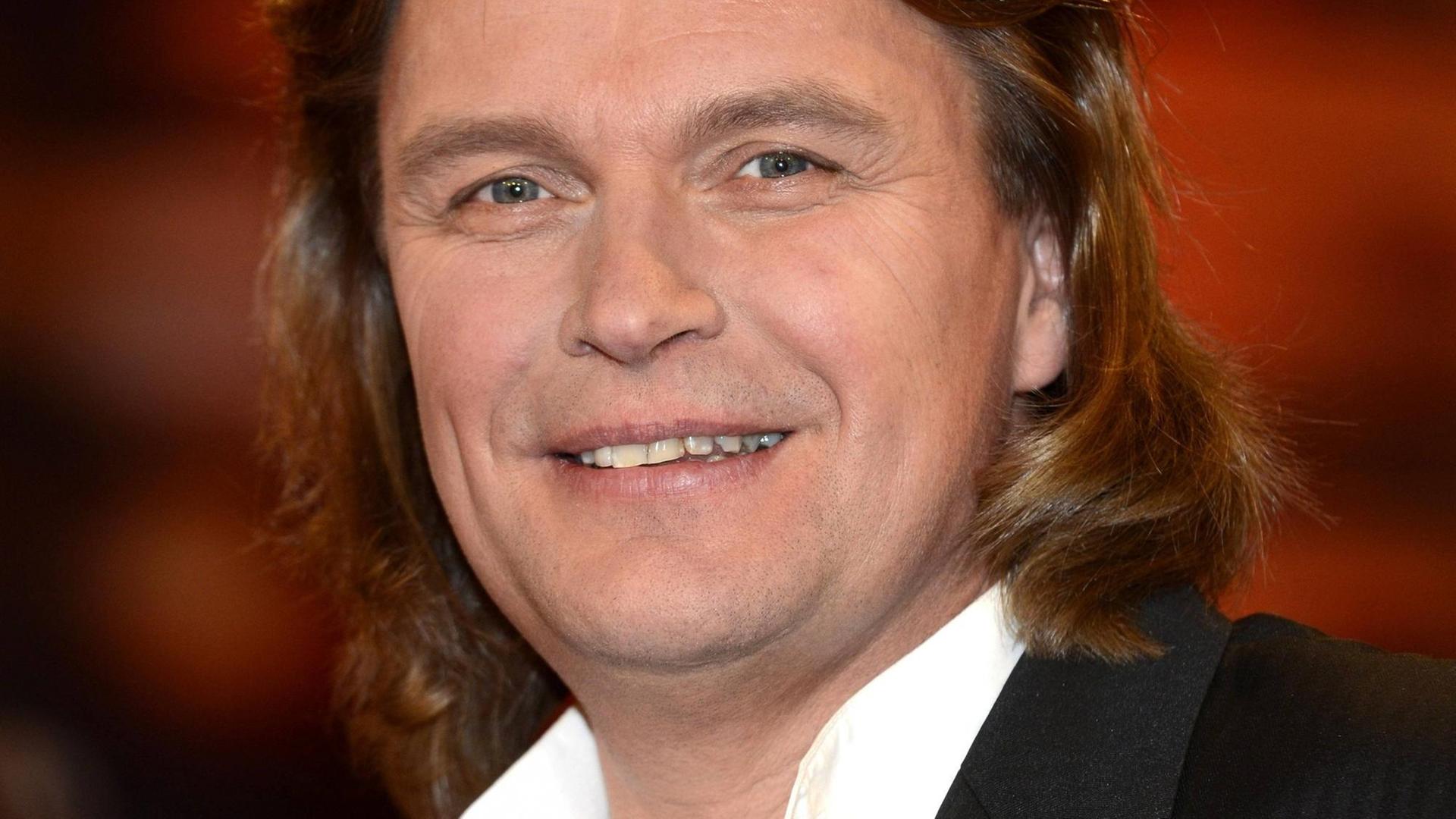 Klaus Florian Voigt steht vor einem roten Hintergrund und lächelt in die Kamera. Klaus Florian Voigt steht vor einem roten Hintergrund und lächelt in die Kamera.