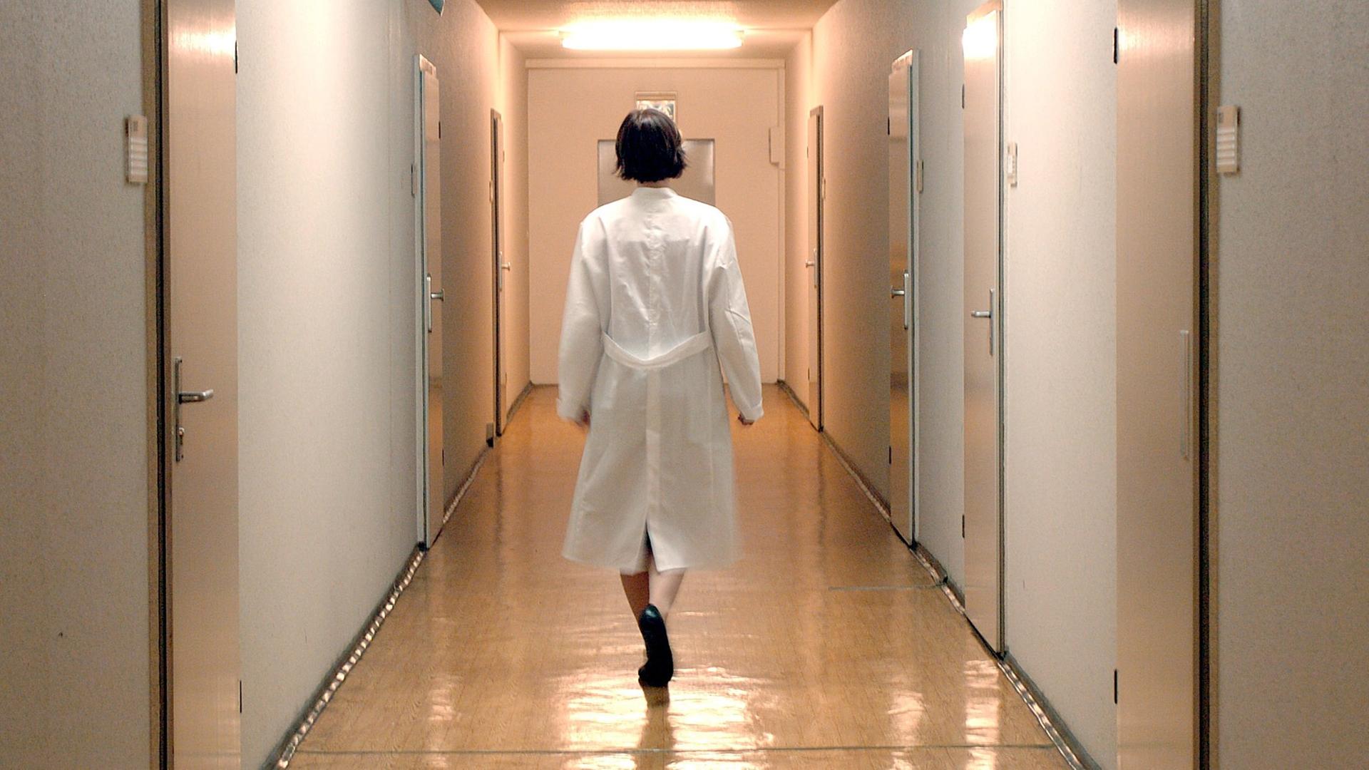 Eine Ärztin läuf allein einen Flur einer Krankenstation in einem Berliner Krankenhaus entlang.