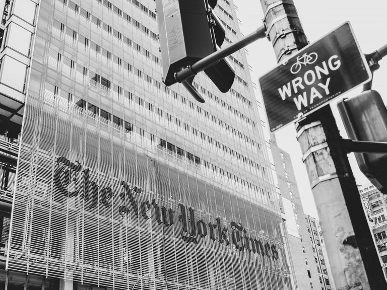 Das Bild zeigt ein Straßenschild mit der Aufschrift "Wrong Way" und dieses steht vor dem New-York-Times-Gebäude.