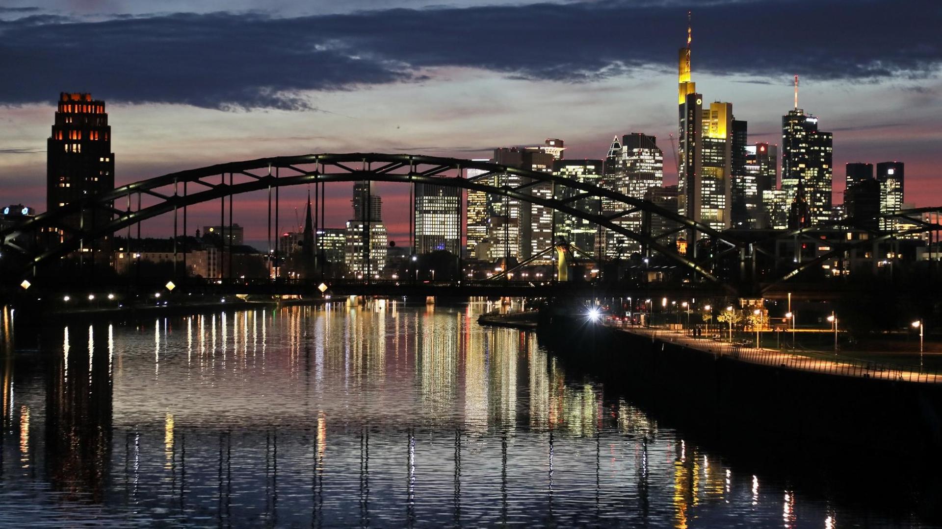 Die Skyline von Frankfurt am Main mit vielen Bankengebäuden spiegelt sich am Abend im Main Die Skyline von Frankfurt am Main mit vielen Bankengebäuden spiegelt sich am Abend im Main