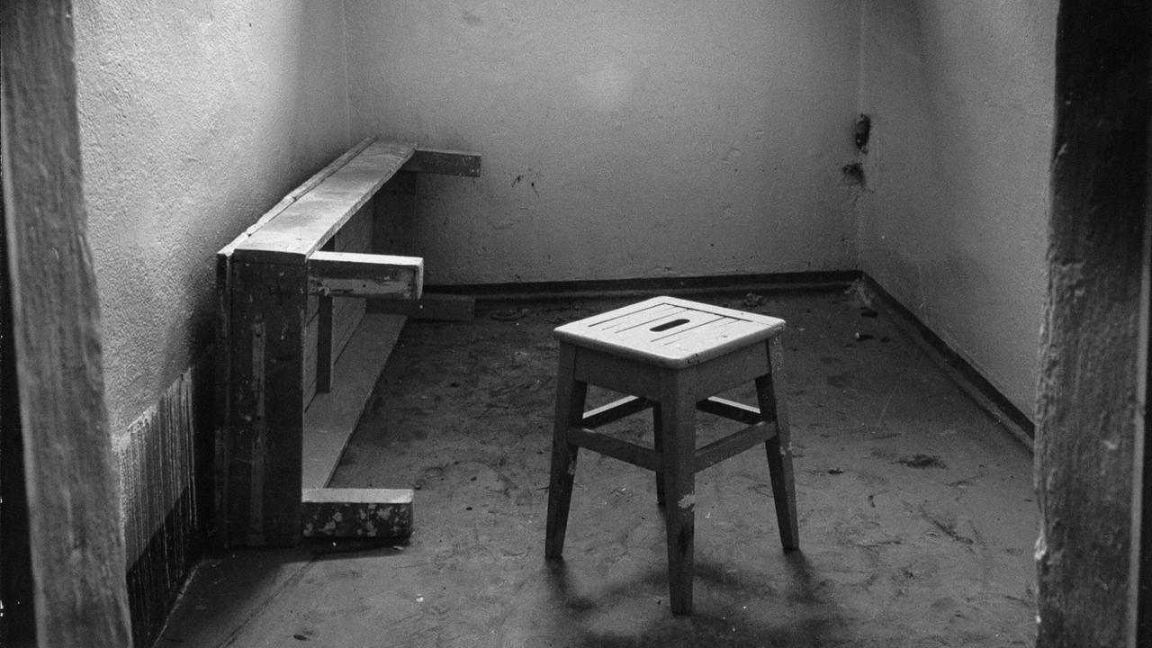 Pritsche, Hocker und ein vergittertes Fenster in einer Einzelarrestzelle Pritsche, Hocker und ein vergittertes Fenster in einer Einzelarrestzelle